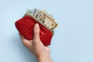 portafoglio con dollari nel femmina mano su blu sfondo. minimalista finanziario concetto foto