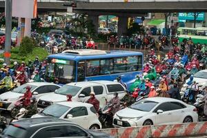 ho chi minh, viet nam - 24 aprile 2023 vietnamita persone indossare casco e impermeabile cavalcata motocicletta nel pesante pioggia e traffico marmellata. foto