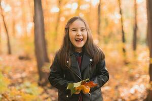 asiatico bambino ragazza ridendo e giocando nel il autunno su il natura camminare all'aperto foto