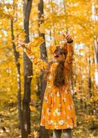 contento bambino ragazza lanci autunno le foglie e ride all'aperto - autunno e stagione concetto foto