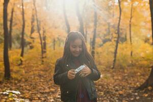 bambino ragazza utilizzando un vecchio stile telecamera nel autunno natura. fotografo, autunno stagione e tempo libero concetto. foto