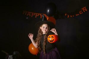 divertente bambino ragazza nel strega costume per Halloween con zucca Jack. foto