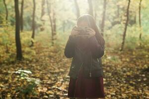 un' poco ragazza prendere un' foto con vecchio retrò telecamera nel autunno natura. tempo libero e passatempo concetto.