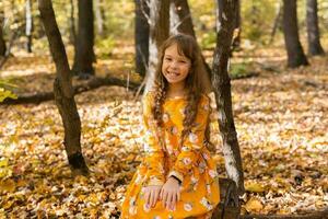 ritratto ragazzo ragazza con autunno arancia le foglie nel un' parco. stile di vita, autunno stagione e bambini concetto. foto