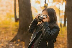 bambino ragazza utilizzando un vecchio stile telecamera nel autunno natura. fotografo, autunno stagione e tempo libero concetto. foto