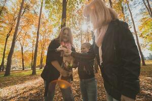 nonna e madre con nipotina avendo divertimento con cane nel autunno stagione. generazione, tempo libero e famiglia concetto foto