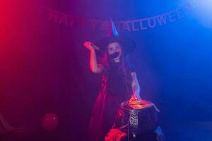 poco strega bambino cucinando pozione nel il calderone su Halloween. foto