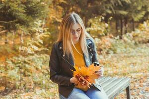 carino smiley donna Tenere autunno le foglie nel autunno parco. di stagione, stile di vita e tempo libero concetto. foto