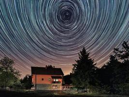tracce stellari sopra la casa. edificio residenziale e le tracce delle stelle nel cielo. il cielo notturno è astronomicamente preciso.