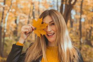 giovane donna con autunno arancia acero foglia al di sopra di autunno stagione sfondo foto