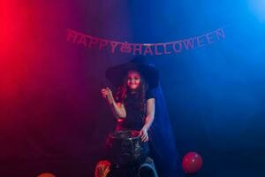 poco strega bambino cucinando pozione nel il calderone su Halloween. foto