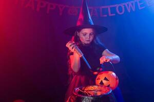 bambino ragazza strega preparazione un' pozione nel il calderone a Halloween vacanze. foto