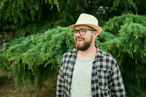 ridendo attraente uomo indossare cappello al di sopra di verde albero sfondo - emozione e vacanza viaggio vacanze concetto foto