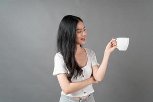 giovane donna asiatica con la faccia felice e la mano che tiene la tazza di caffè coffee foto