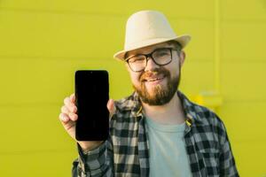 caldo offerta. contento tipo detiene cellulare con nero copia spazio e sorridente. umano emozioni facciale e posto per pubblicità e testo foto