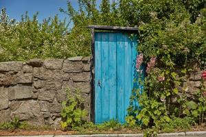 Muro di pietra e porta blu sull'isola di Bornholm a Svaneke, Danimarcaden foto