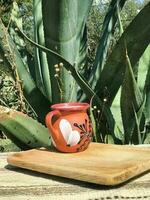 pulque, il messicano bere, servito nel un terracotta tazza in mezzo della natura vivace tavolozza foto