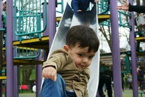 carino asiatico pakistano bambino è godendo il bellissimo soleggiato e freddo giorno a guerra pubblico parco di luton cittadina di Inghilterra UK. Basso angolo io foto