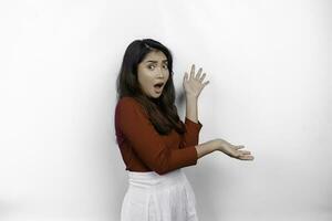 scioccato asiatico donna indossare rosso maglietta, puntamento a il copia spazio su accanto suo, isolato di bianca sfondo foto