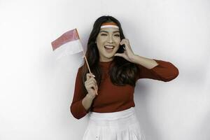contento sorridente indonesiano donna Tenere dell'Indonesia bandiera e mostrando amore cartello per celebrare Indonesia indipendenza giorno isolato al di sopra di bianca sfondo. foto