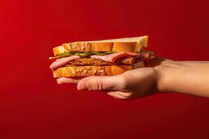 mano Tenere gustoso Sandwich su un' rosso sfondo. ai generato foto