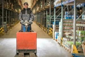 caucasico lavoratore nel uniforme con pallet Jack foto