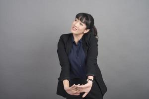 donna d'affari sorridente in blazer su sfondo grigio foto