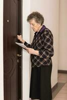 vecchio donna è vicino per il porta di sua vicino. foto