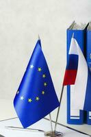 Due bandiere di il Unione Europea e Russia su un' bianca tavolo. avvicinamento foto