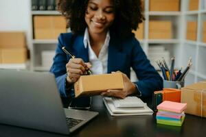 giovane donna Tenere un' smartphone, tavoletta mostrando pagamento successo e credito carta con giallo pacco scatola come in linea shopping concetto foto