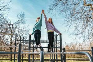 coppia di femmina atleti avendo divertimento mentre arrampicata su sport metallo struttura all'aperto foto