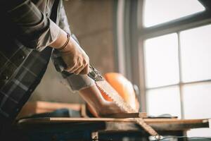 asiatico falegname Lavorando con attrezzatura utensili su di legno tavolo nel carpenteria negozio. concetto Lavorando di falegname. professionale Lavorando di legno uomo. foto