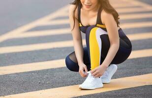 vicino su di femmina corridore legatura sua scarpe preparazione per un' correre su all'aperto strada foto