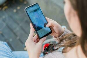 giovane donna controllo sua cellula Telefono, seduta nel un' parco. selettivo messa a fuoco. messa a fuoco su inteligente Telefono. foto