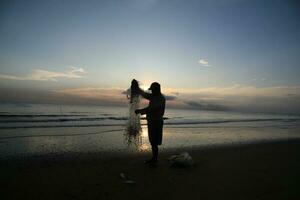 il bellezza di il tramonto su il spiaggia con il silhouette di un' pescatore foto