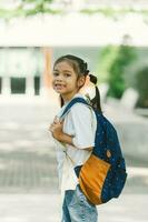 ritratto di carino poco asiatico scolara con zaino nel il scuola foto