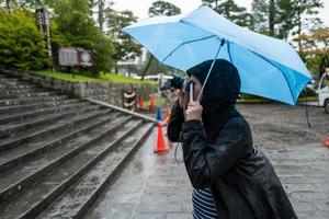 una turista femla a nikko che fa foto sotto la pioggia