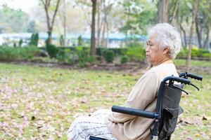 asiatico anziano o anziana signora anziana paziente dolore al ginocchio sulla sedia a rotelle nel parco, concetto medico sano e forte. foto
