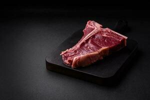 crudo succoso Manzo t-bone bistecca con sale, spezie e erbe aromatiche foto