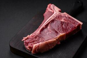 crudo succoso Manzo t-bone bistecca con sale, spezie e erbe aromatiche foto