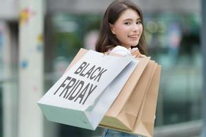 concetto di venerdì nero, donna che tiene molte borse della spesa e sorride nel negozio durante il processo di acquisto