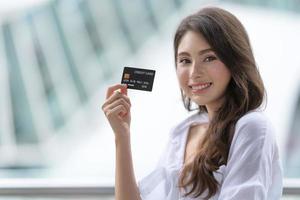 concetto di venerdì nero, donna che tiene la carta di credito e sorride vicino al negozio foto