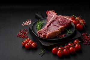 crudo succoso Manzo t-bone bistecca con sale, spezie e erbe aromatiche foto