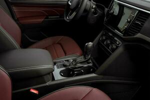 lato Visualizza di il interno di un' lussuoso auto Pannello, rosso pelle sedili, automatico trasmissione, timone ruota e toccare schermo foto