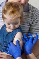 una bambina con suo padre nell'ambulatorio della clinica viene vaccinata contro il coronavirus.il concetto di vaccinazione, immunizzazione, prevenzione contro covid-19. foto