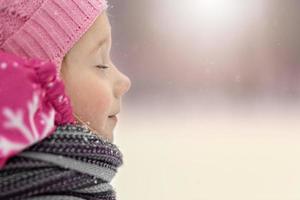 ritratto di una bambina in primo piano rosa. un bambino si gode la nevicata. vacanze di Natale foto