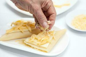 parmigiano lasagne preparazione. copertura il triangoli di Lasagna con formaggio foto