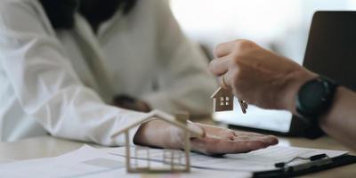 agente immobiliare che tiene la chiave di casa al suo cliente dopo aver firmato un contratto in ufficio, concetto di immobile, trasloco o affitto di proprietà