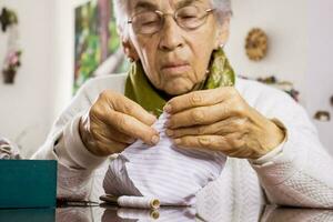 anziano donna cucire un' fatti in casa viso maschera durante il covid 19 pandemia foto