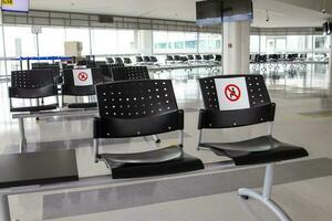 vuoto wating camera a un aeroporto durante covid 19 pandemia con sociale distanziamento segni su sedie foto